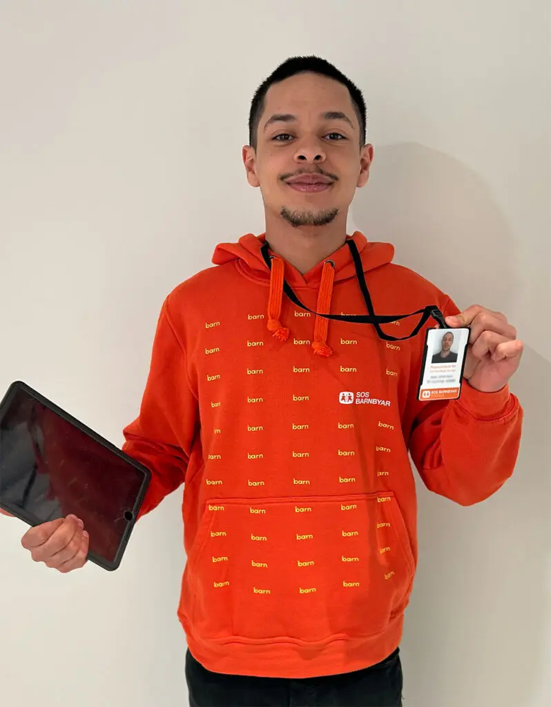 Representant för SOS Barnbyar iklädd orange luvtröja och ID-bricka.