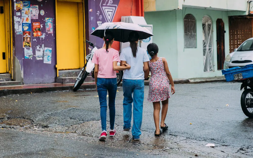 Tre flickor tar skydd under ett paraply