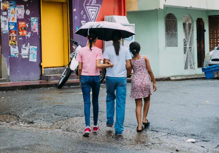 Tre flickor tar skydd under ett paraply