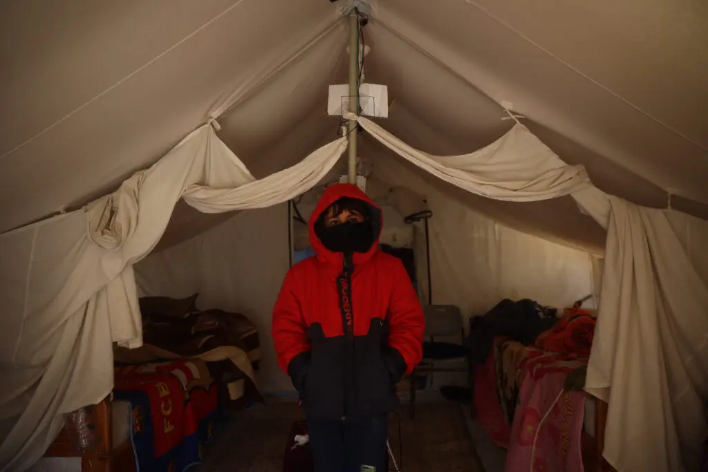 Påpälsad person står inne i ett tält i Gaza