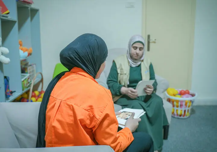 Ungdom i orange tröja bakifrån pratar med personal