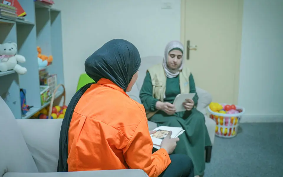 Ungdom i orange tröja bakifrån pratar med personal