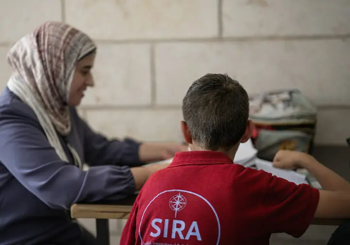 pojke i röd tröja bakifrån sitter och studerar med en kvinna