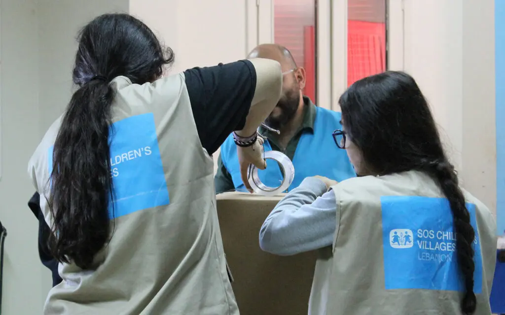 Hjälparbetare i Libanon med SOS Barnbyars västar packar kartonger