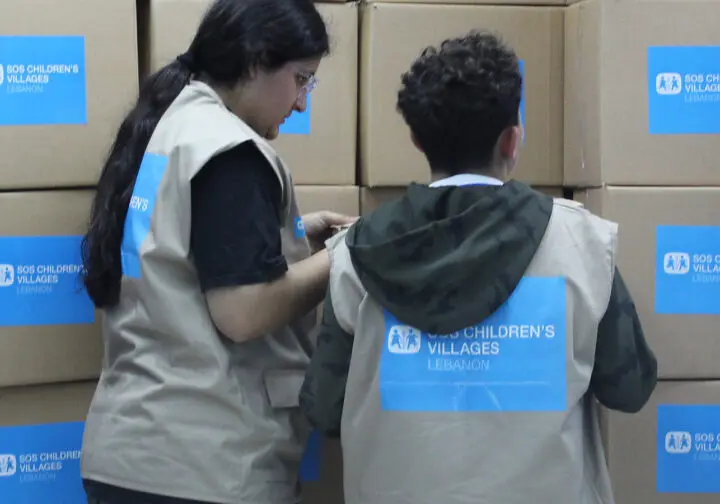 En vägg av kartonger med nödhjälp och två kvinnor i västar