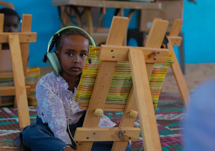 flicka med hörlurar framför staffli och ser ledsen ut