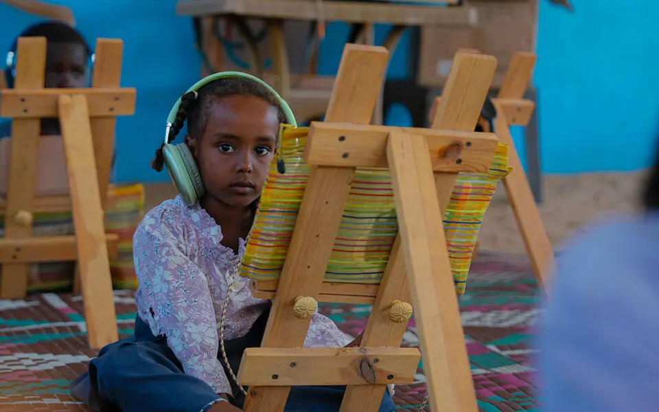 flicka med hörlurar framför staffli och ser ledsen ut