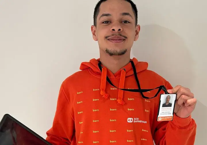 Representant för SOS Barnbyar iklädd orange luvtröja och ID-bricka.