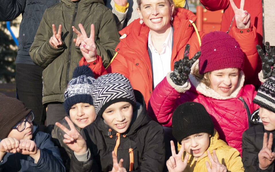 ukraniska barn gör peace-tecken och tittar in i kameran.