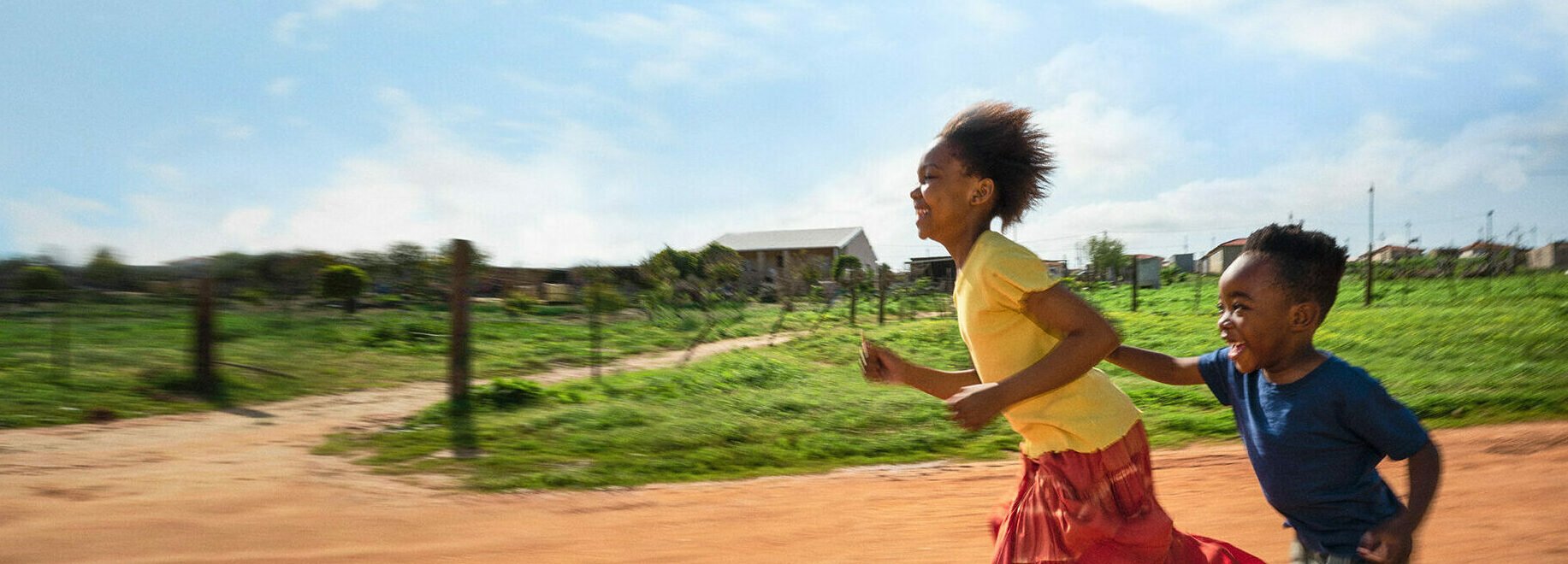 Två glada barn som springer. En flicka och en pojke.