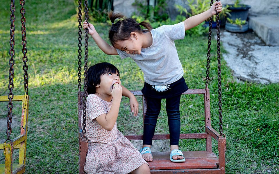 Två barn som leker på en gunga.