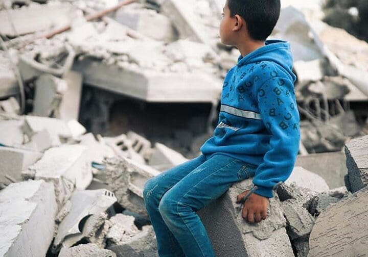Barn i Gaza vid en förstörd byggnad.