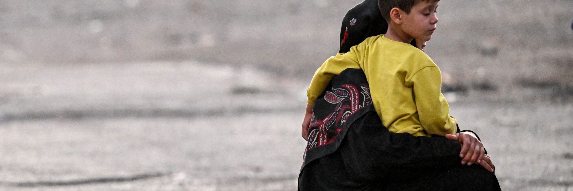 Pojke som sitter i en kvinnas knä bredvid väskor och vattenflaskor.