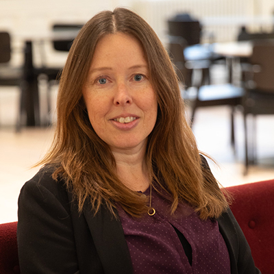 Kvinna i långt brunt hår tittar in i kameran