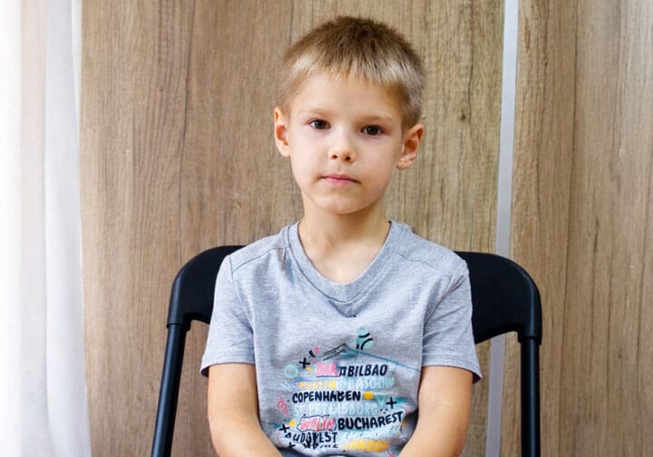 En pojke som sitter på en stol.