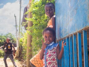 Två flickor utomhus lutar sig mot blå vägg