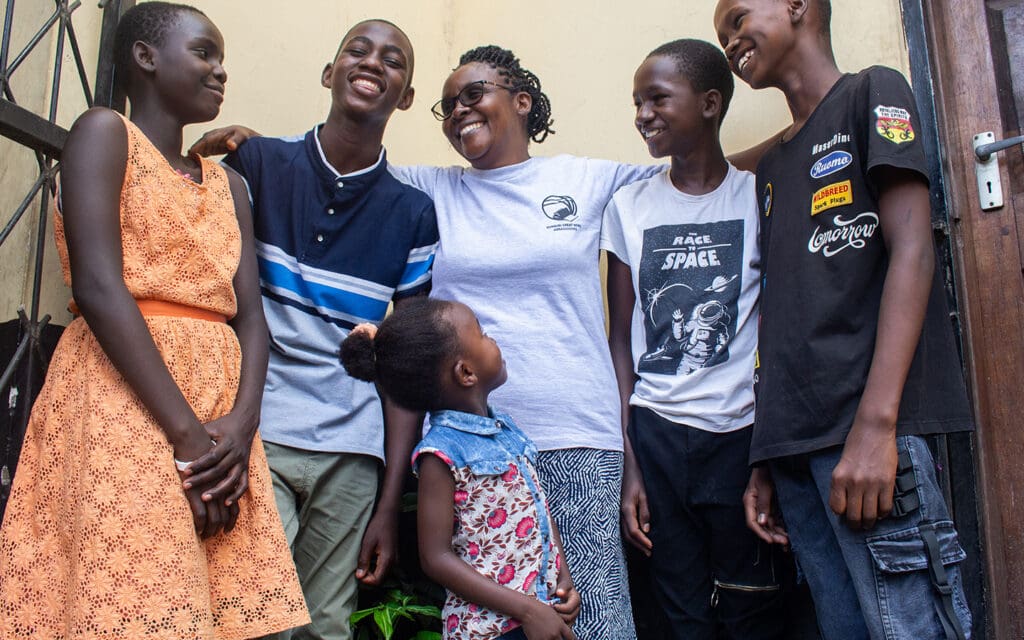 Mamma står med fem barn utomhus