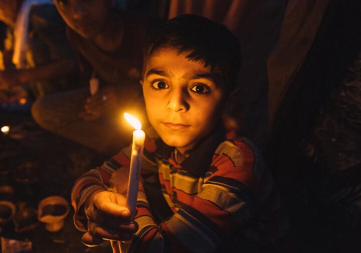 allvarlig pojke med bruna ögon håller ett ljus