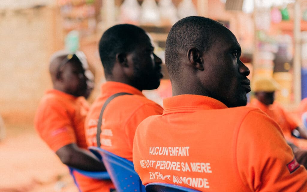 män i orangea tröjor bakifrån