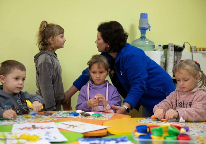 Barn och SOS-personal som sitter vid ett bord och pysslar.