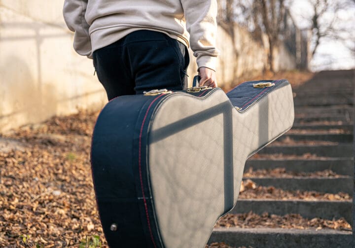 Ungdom bakifrån går ensam med sin gitarr