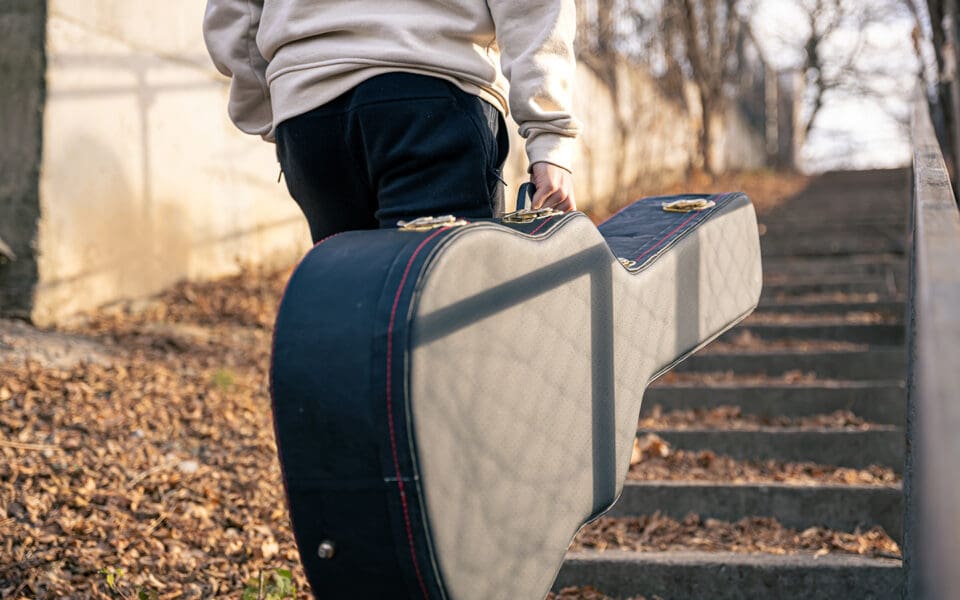 Ungdom bakifrån går ensam med sin gitarr