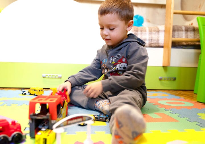 Pojke på golvet leker med lastbil