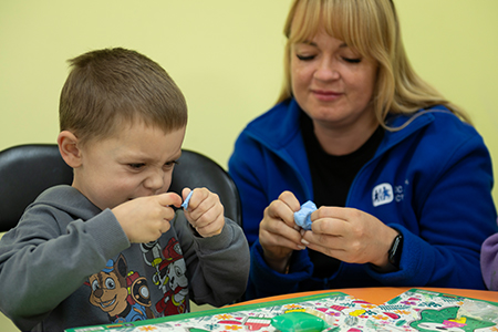 pojke leker med en stöttande vuxen vid sin sida