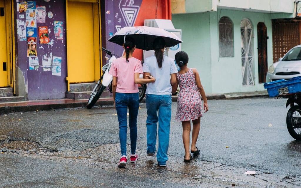 Tre flickor tar skydd under ett paraply