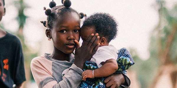 Barn i skolåldern håller en baby