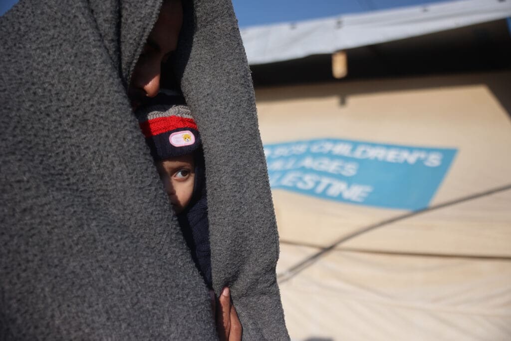 Barn tittar fram under en filt