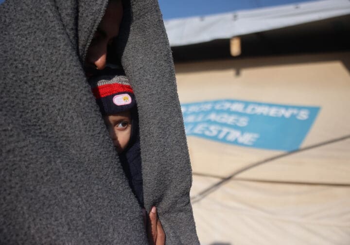 Barn tittar fram under en filt