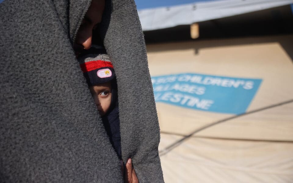 Barn tittar fram under en filt