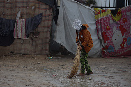 barn i kyla och regn sopar vatten utanför ett tält