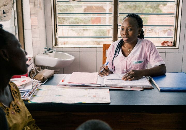 Barnmorska sitter vid bord och pratar med patient