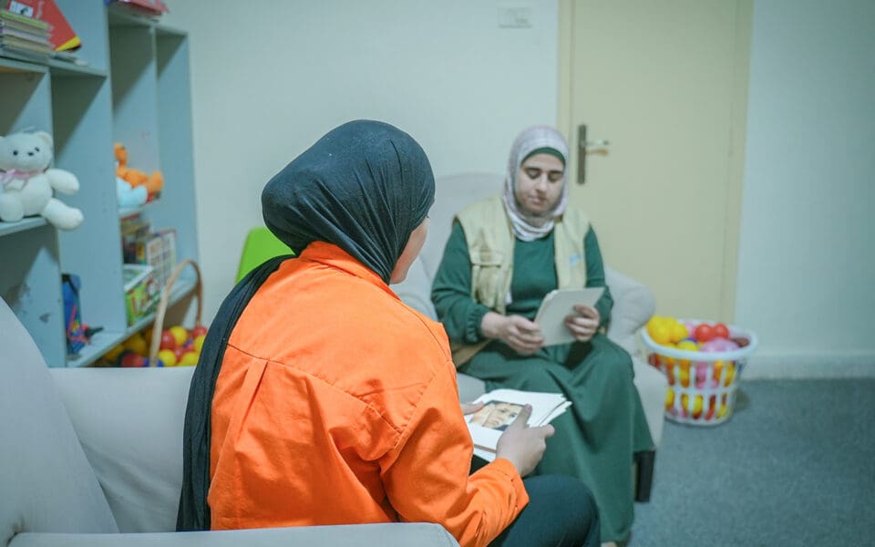 Ungdom i orange tröja bakifrån pratar med personal