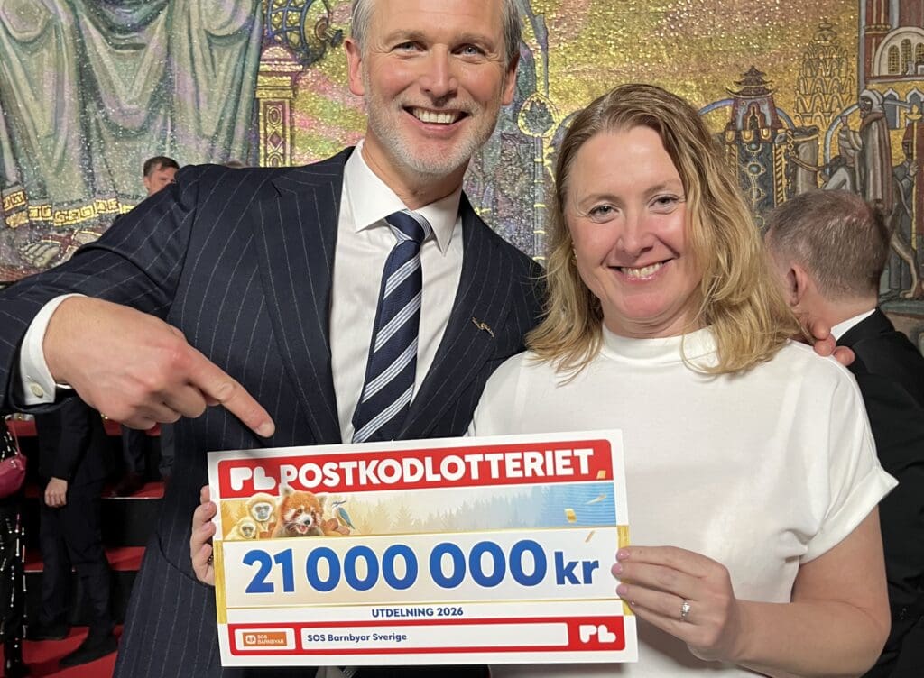 Två personer håller i en stor check och ler