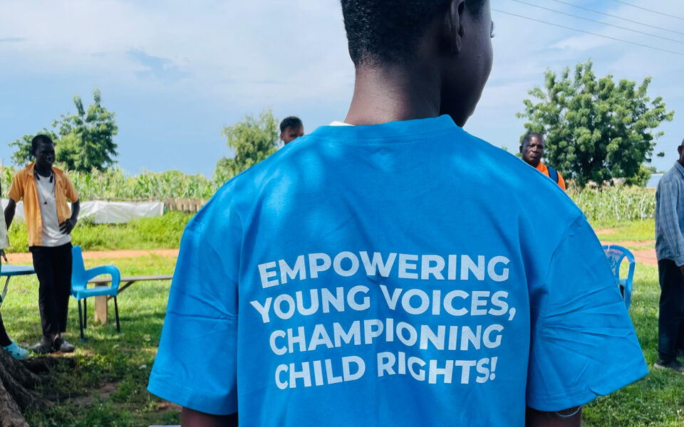 pojke i Ghana bakifrån med blå t-shirt med texten empowering young voices
