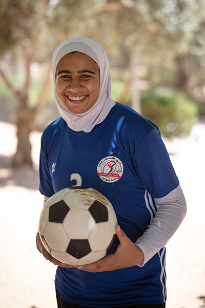Glad flicka håller i en fotboll
