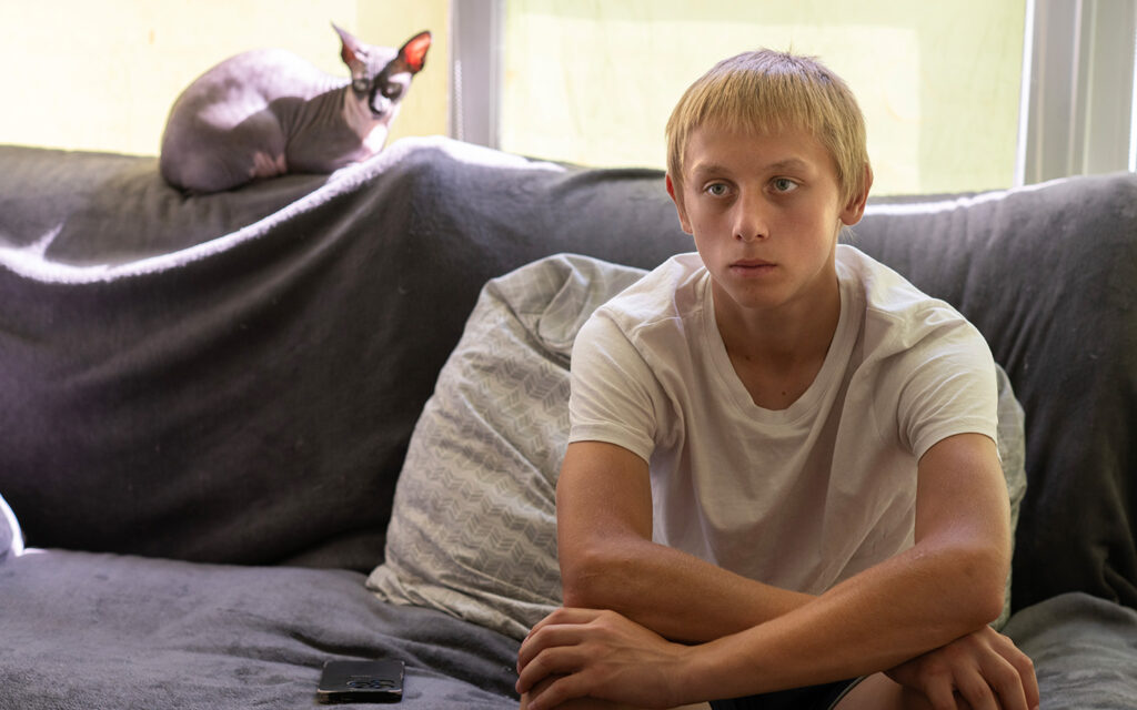 Sorgsen pojke i en soffa