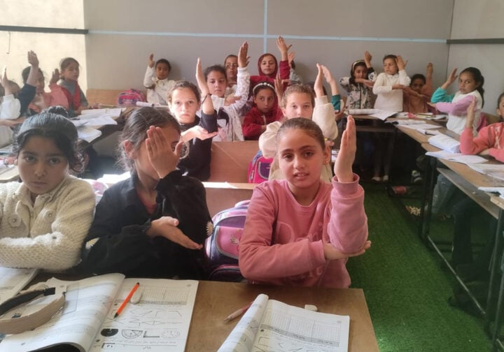 barn sitter i ett temporärt klassrum i ett tältläger i gaza
