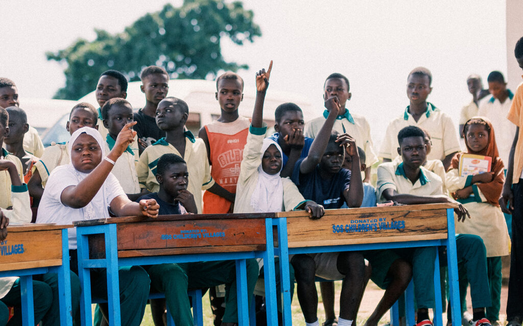 en grupp engagerade ungdomar i ghana sitter vid bord utomhus