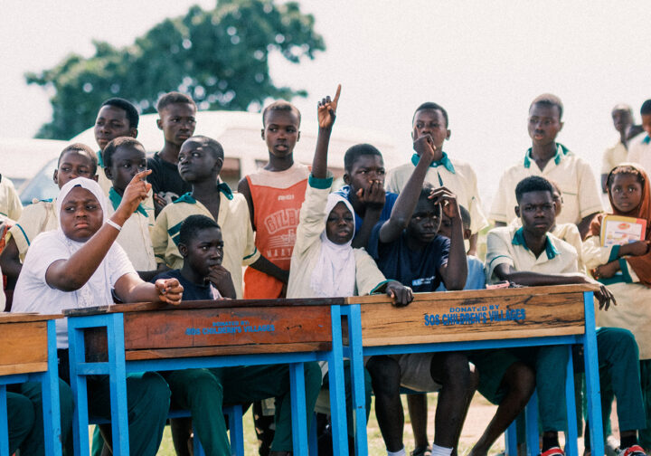 en grupp engagerade ungdomar i ghana sitter vid bord utomhus