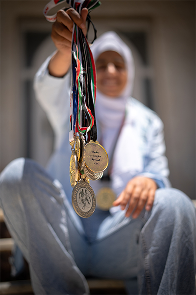 Flicka i Jordanien håller upp medaljer från fotbollsvinster