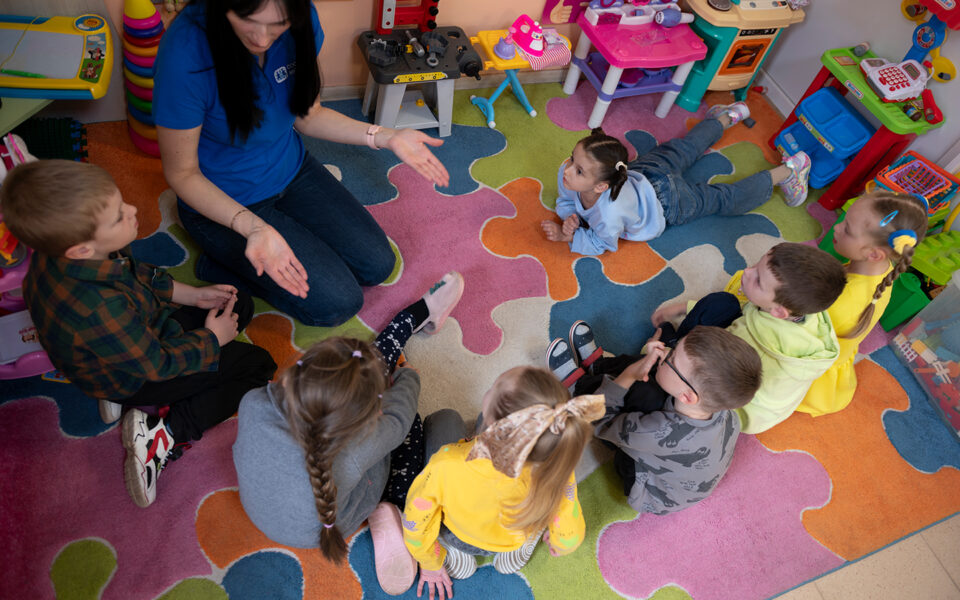 barn sitter i ring medan en pedagog berättar något för dem