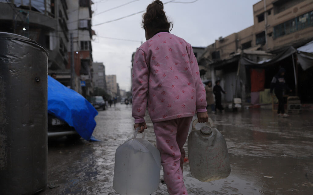flicka i rosa kläder i gaza syns bakifrån bära tunga vattentankar