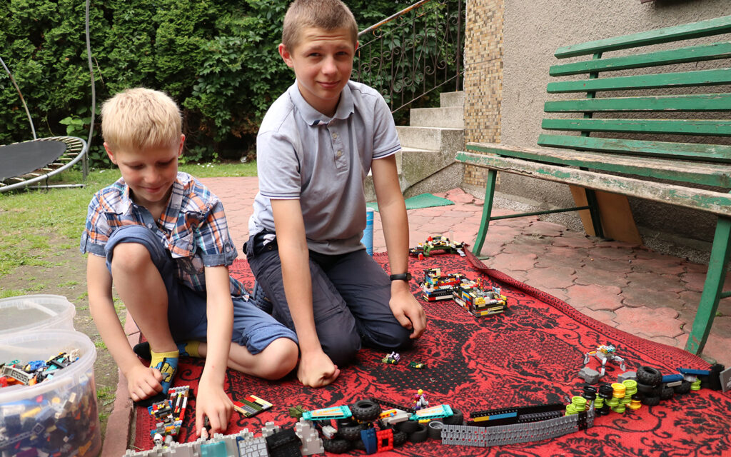 två pojkar bygger lego på en filt utomhus