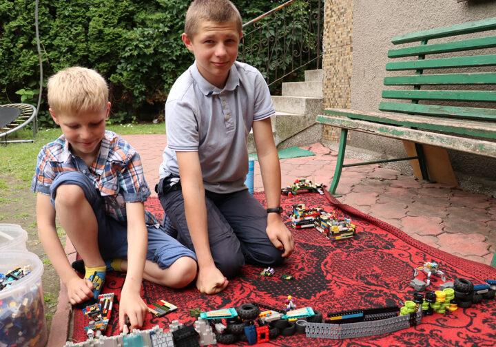 två pojkar bygger lego på en filt utomhus